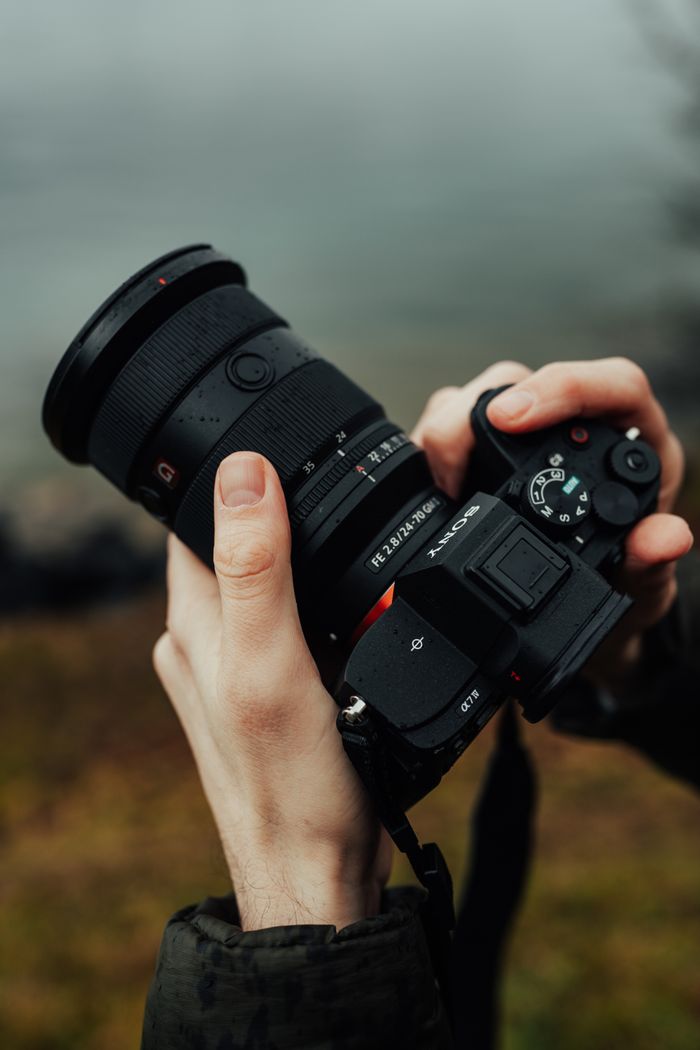 Close-up of hands holding a camera in an outdoor environment, perfect for photography themes.